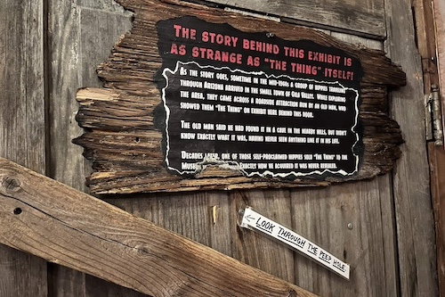 Wooden sign explaining the origin story for an exhibit called 'The Thing'